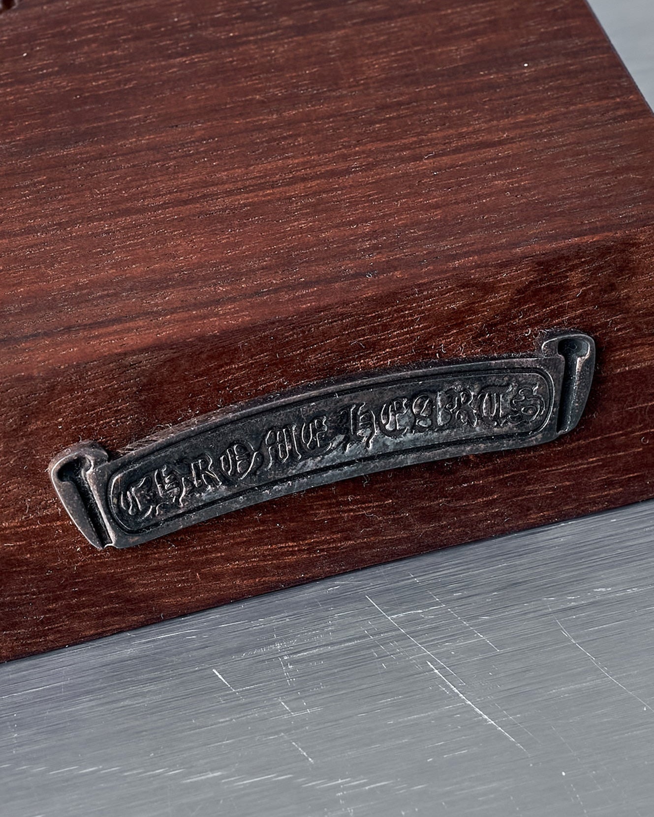 Wooden block with two holes and a metal badge on a gray background