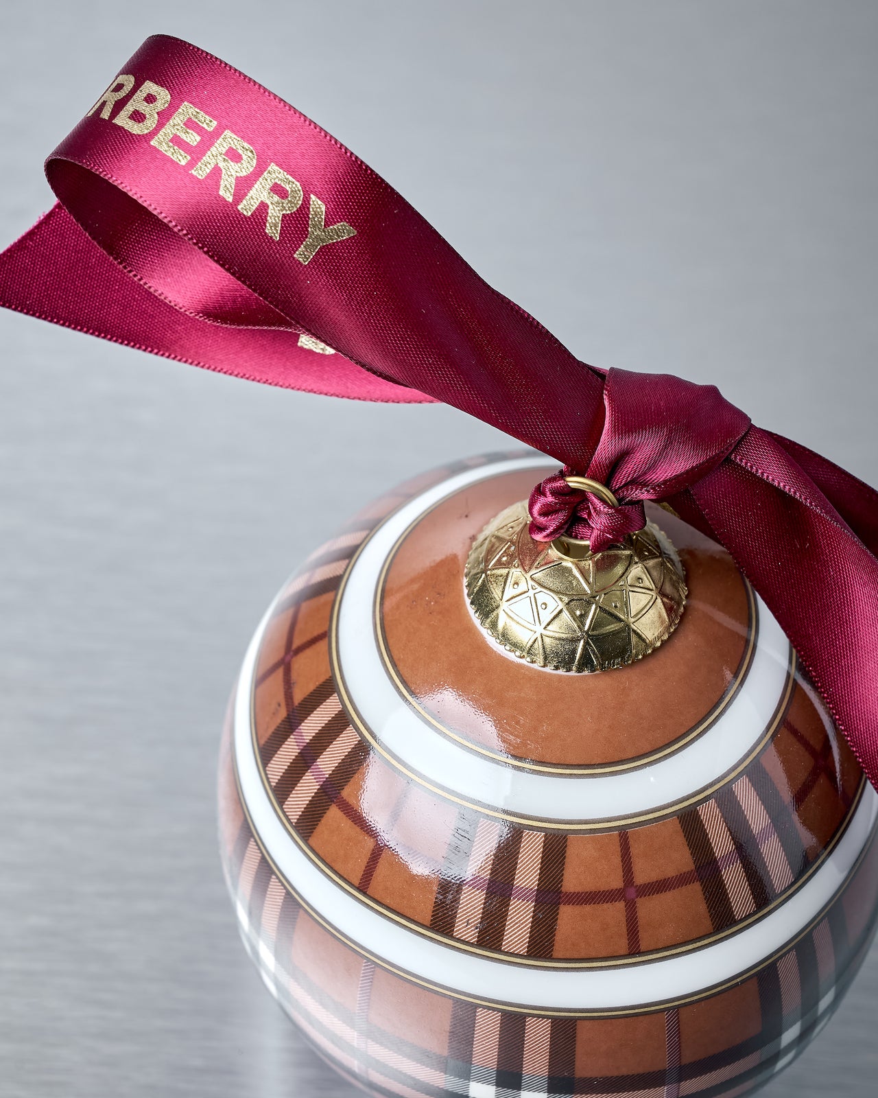 Decorative ornament with Burberry plaid pattern and ribbon on a gray background
