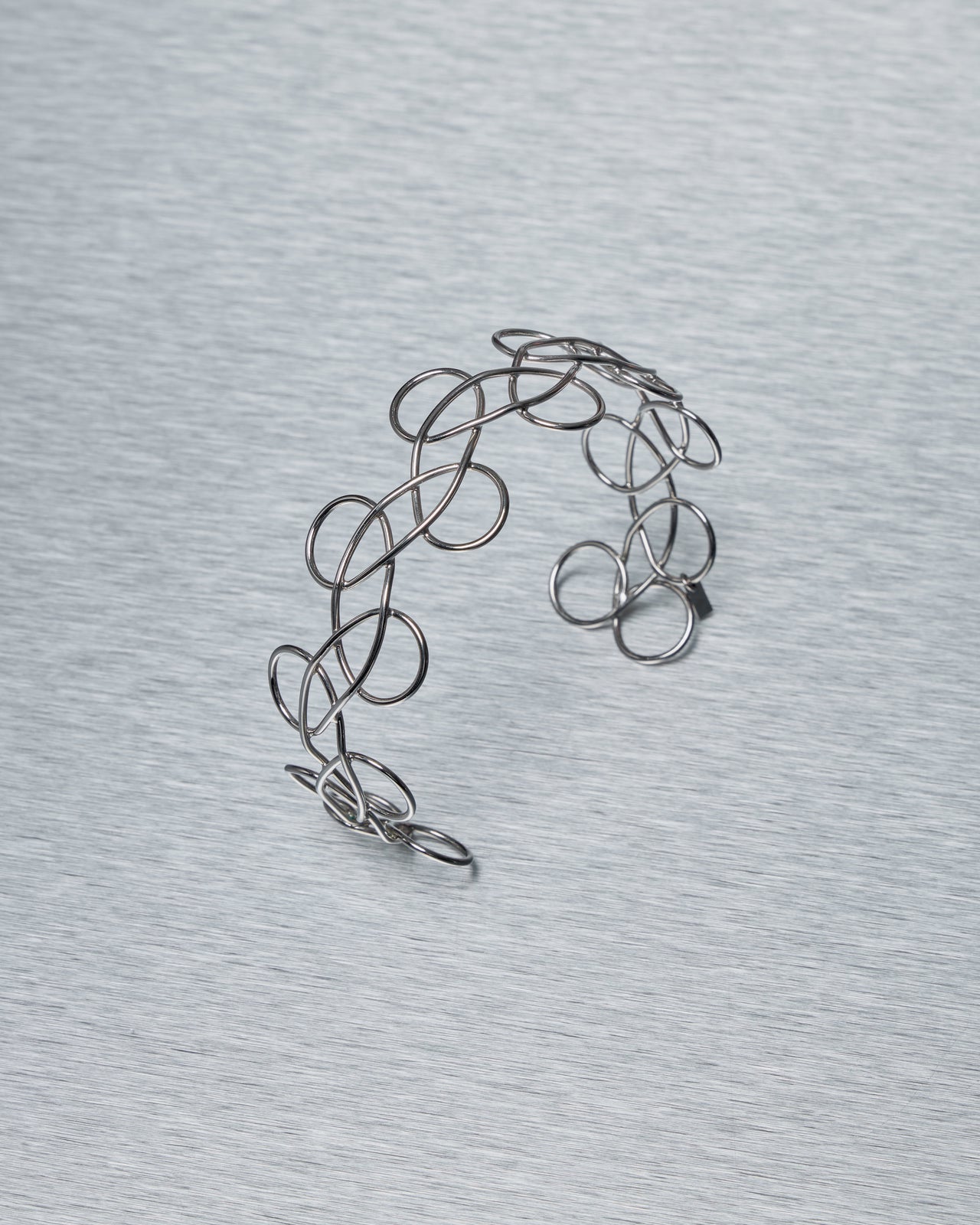 Silver wire Acne Studios choker necklace on a gray background
