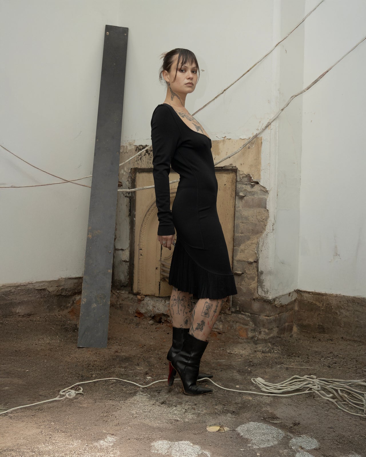 Person wearing a black Alaia dress and high heels in an industrial setting