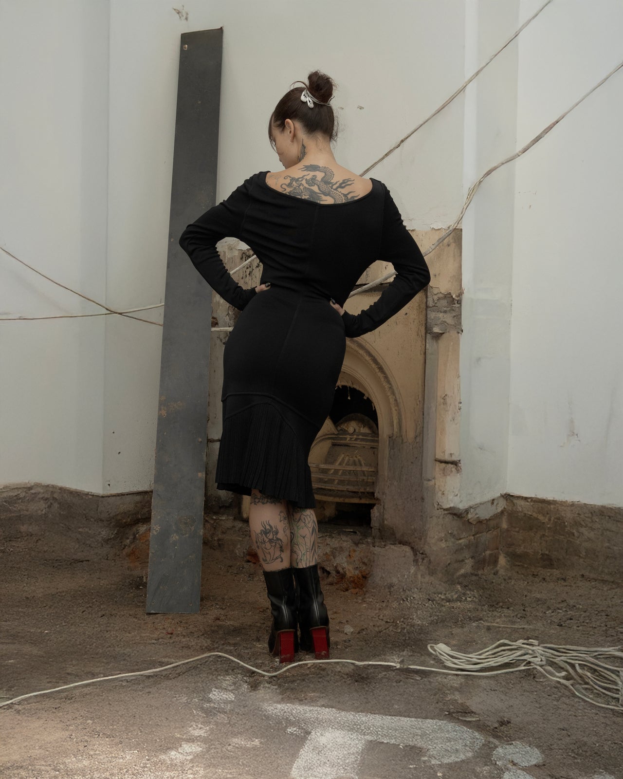 Person wearing a black Alaia dress and high heels in an industrial setting