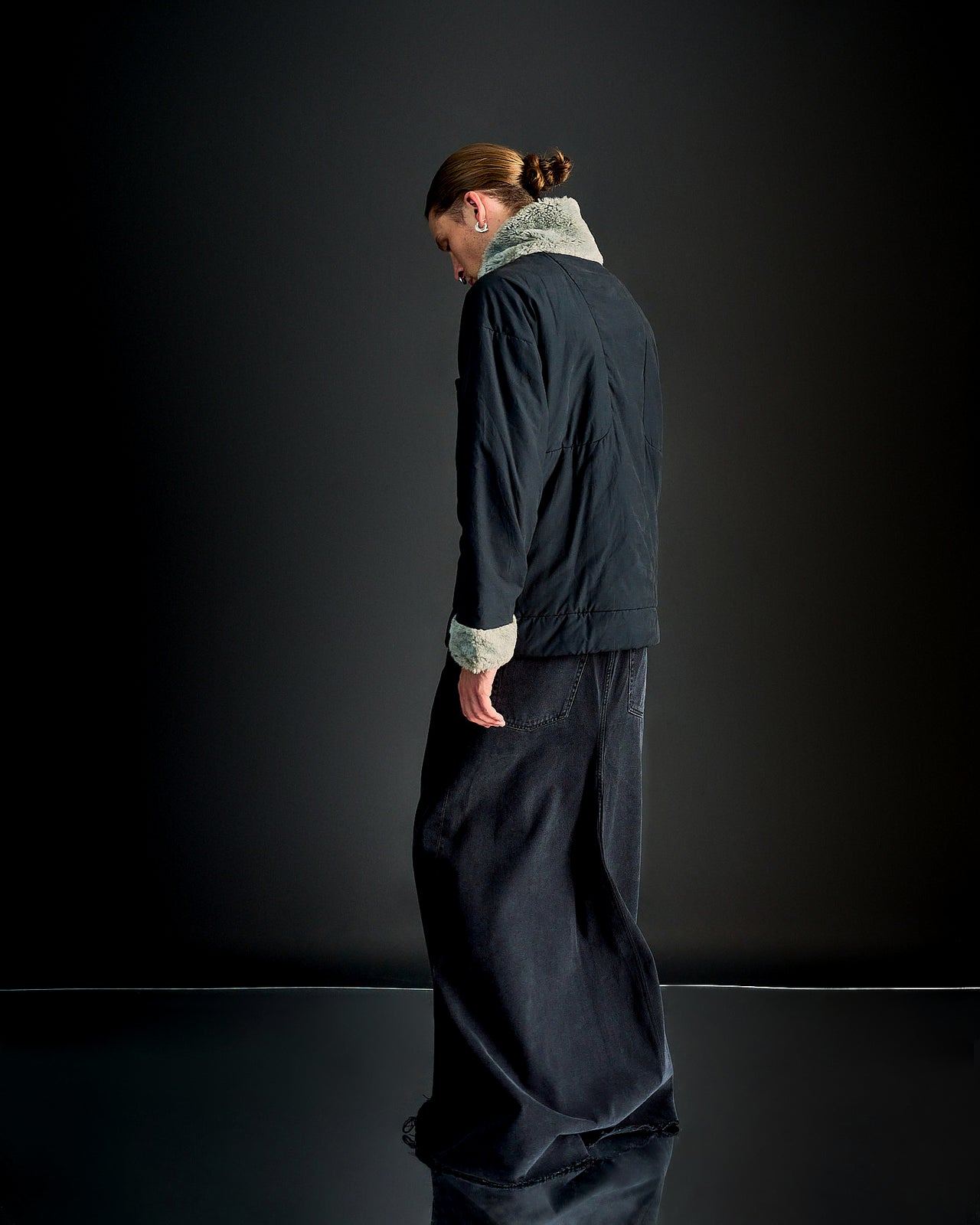 A person viewed from the back wearing a black Alexander Mcqueen shearling collar padded pullover with a visible external breast pocket.