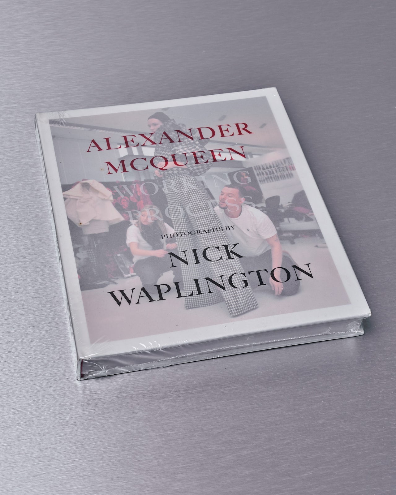 Cover of the book 'Alexander Mcqueen Working Process: Photographs by Nick Waplington' featuring a white background with the author's name and the title of the book.