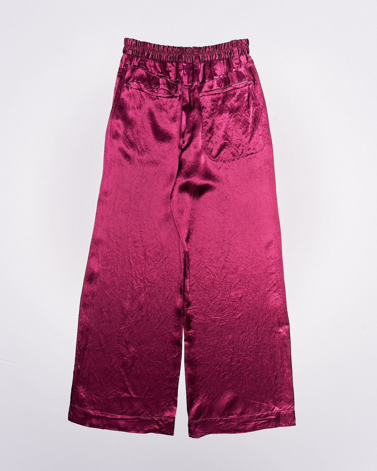 Magenta shiny Ann Demeulemeester pants with a high waist and loose fit, displayed against a plain white background. The fabric has a smooth, shiny texture.