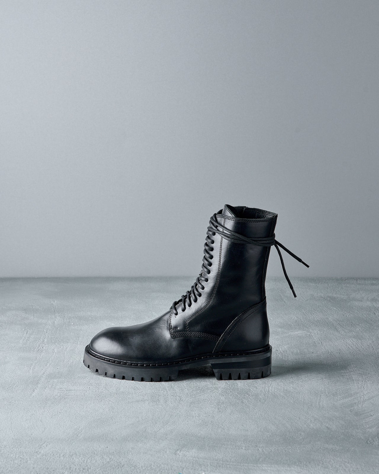 Black leather Ann Demeulemeester boot on a gray background