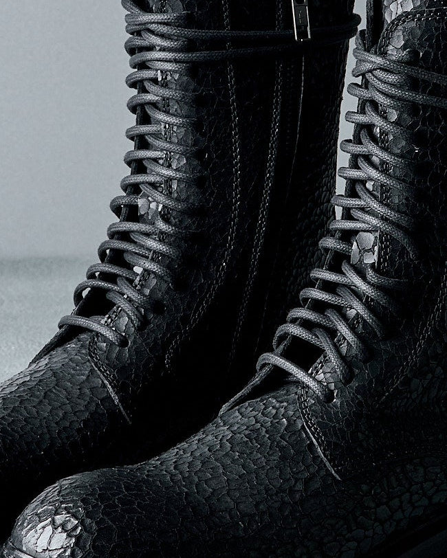 Black leather Ann Demeulemeester boot with textured sole on a gray background