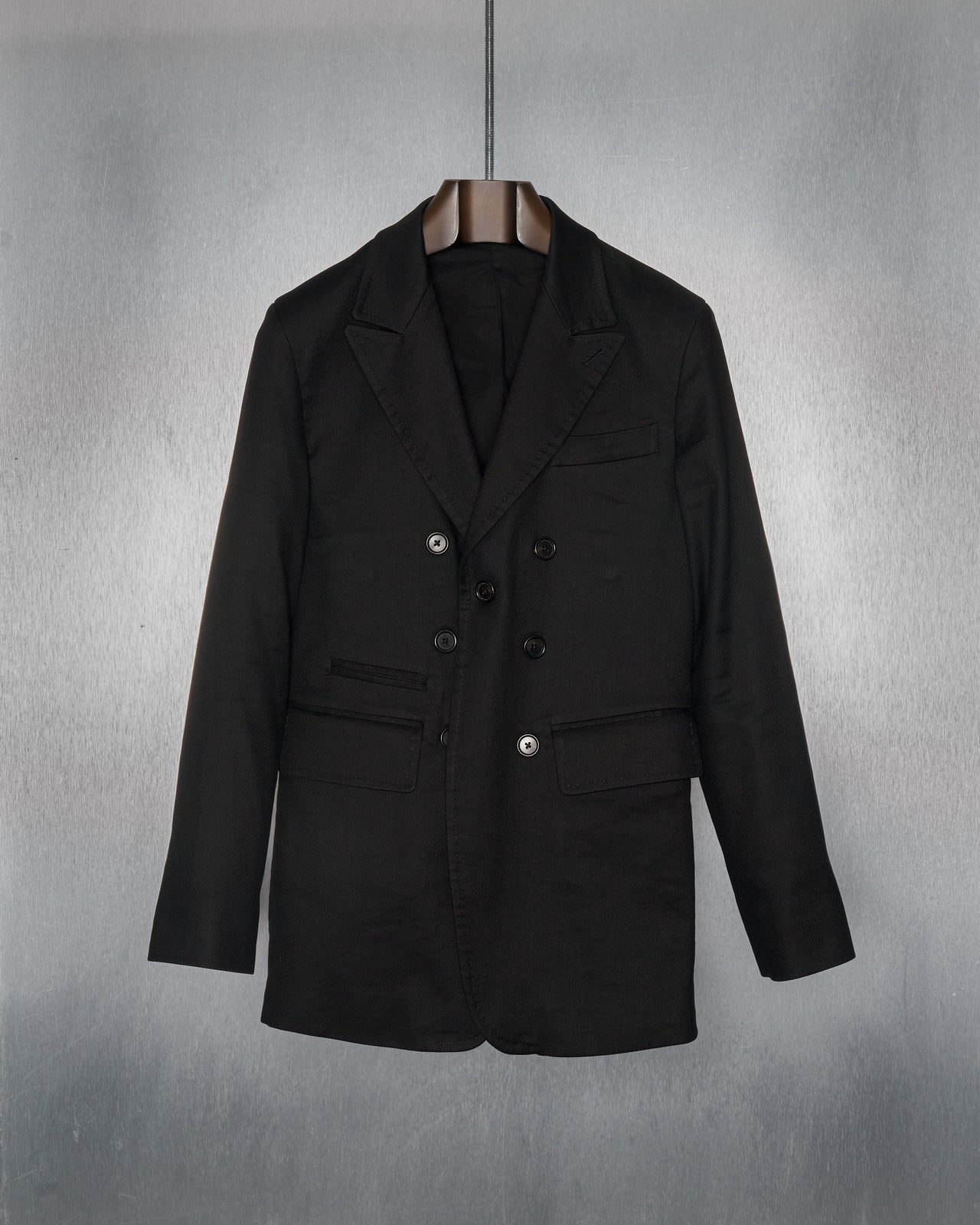 A black peak lapel twill blazer from Ann Demeulemeester with a single-button closure, displayed on a grey background.