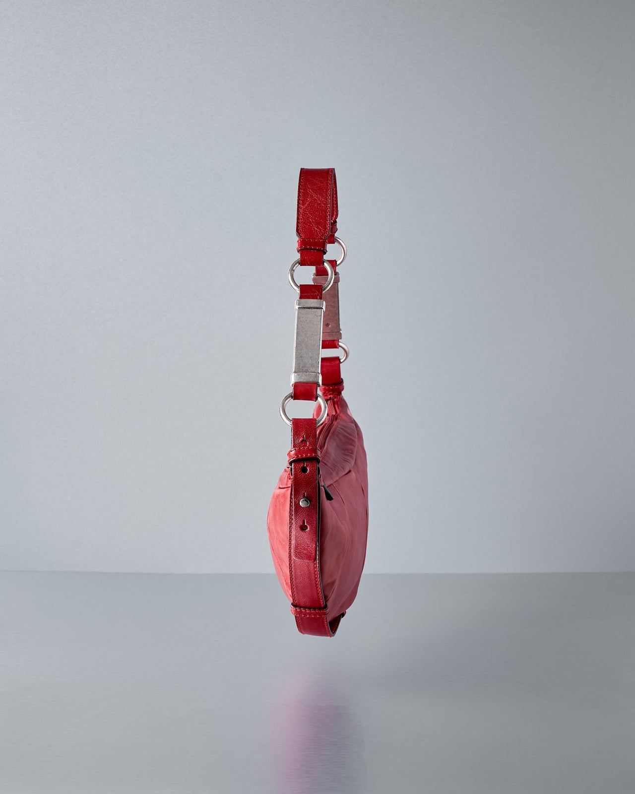 Red leather bag with a strap on a gray background