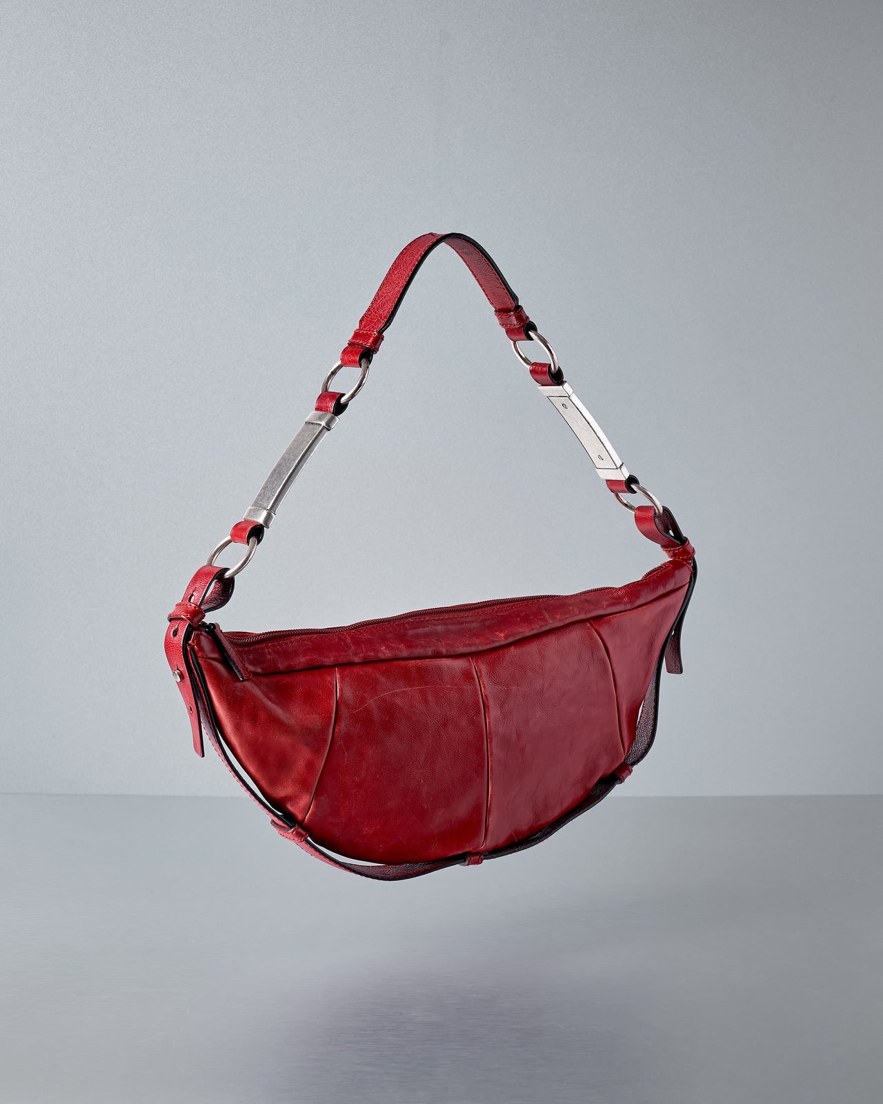 Red leather bag with a strap on a gray background