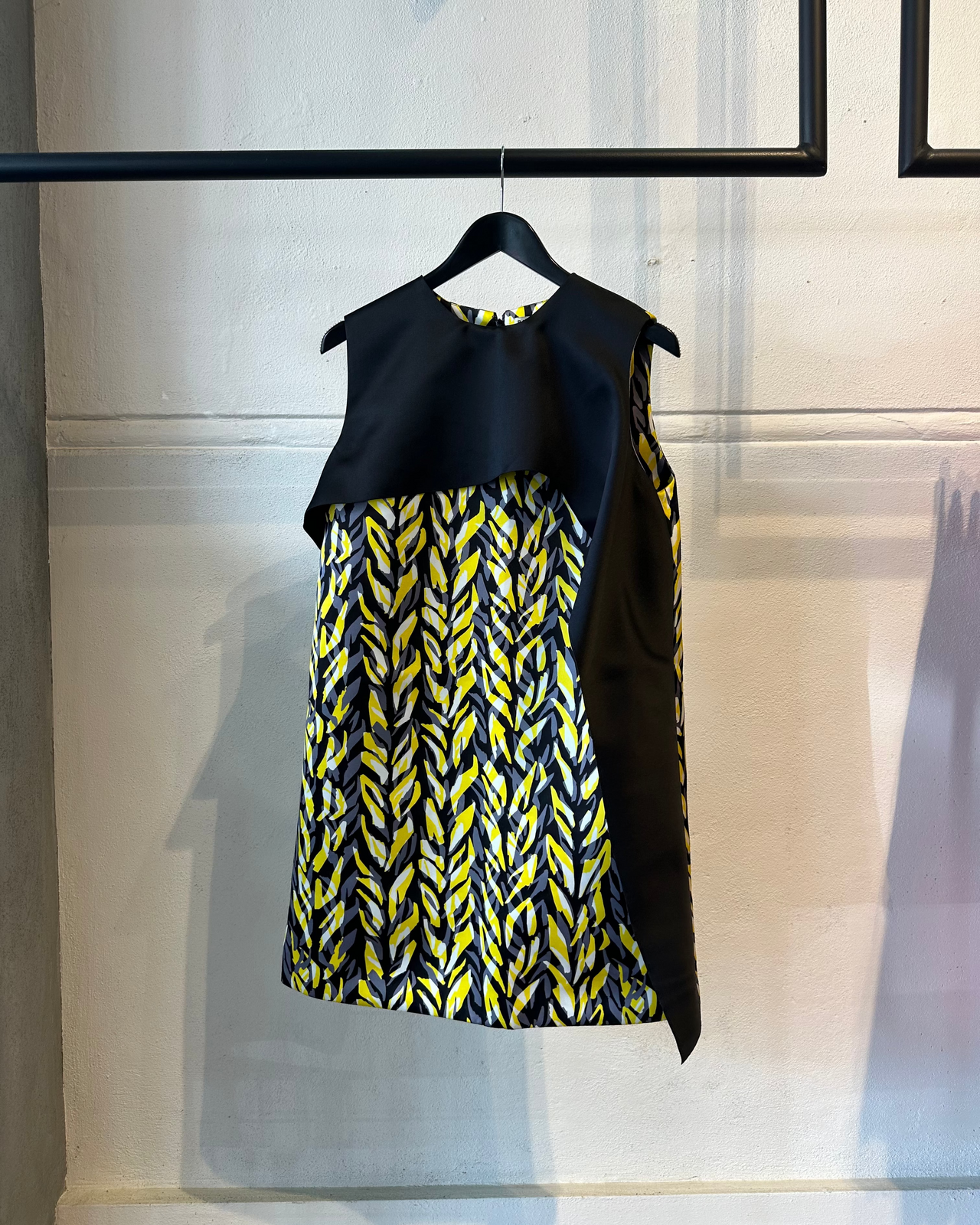 Black and yellow Balenciaga patterned dress on a hanger against a neutral background