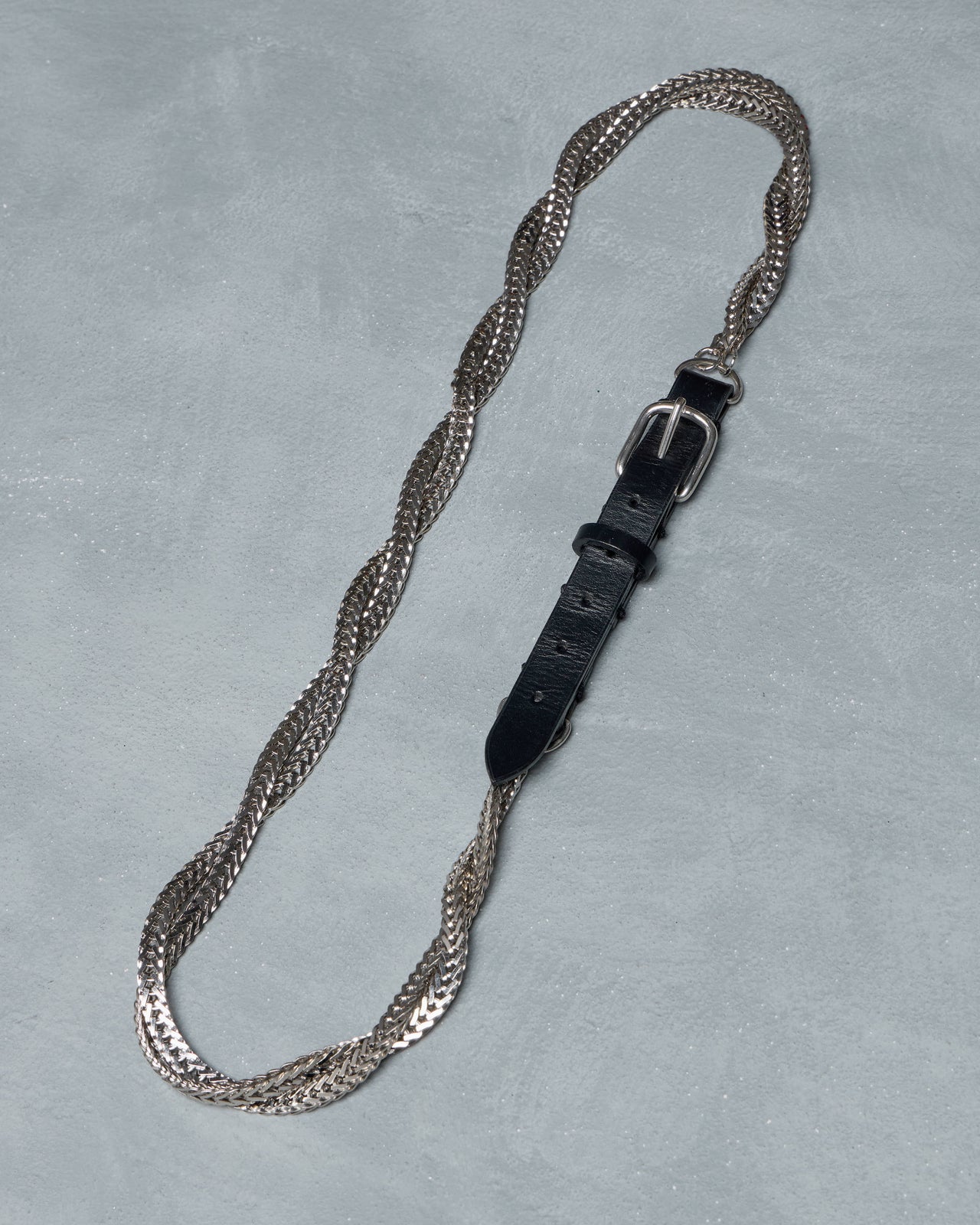 Silver Balmain chain belt with a black leather strap and buckle on a light gray background