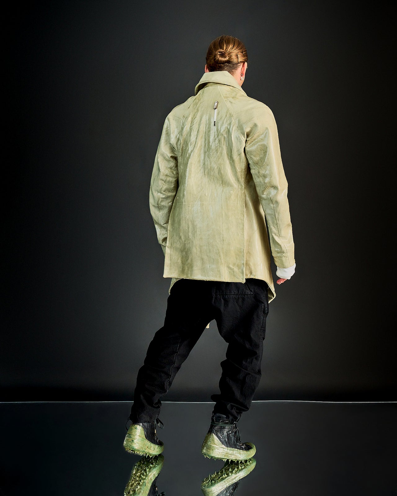 A person wearing an oversized double-breasted Boris Bidjan Saberi lamb leather jacket with raglan panels, exaggerated lapels, and a asymmetric four-button front.