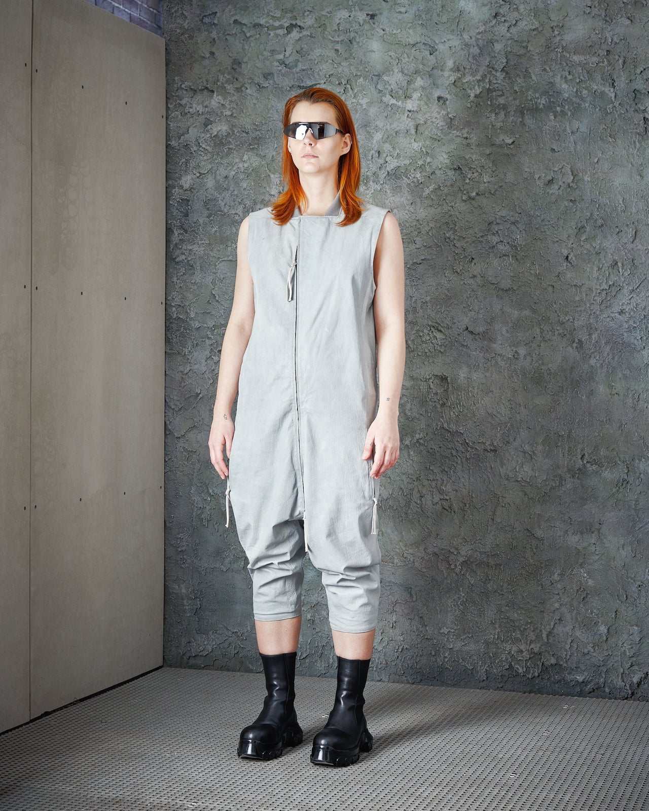 Model wearing a stylish Boris Bidjan Saberi outfit with a long coat and black accents on a dark runway.