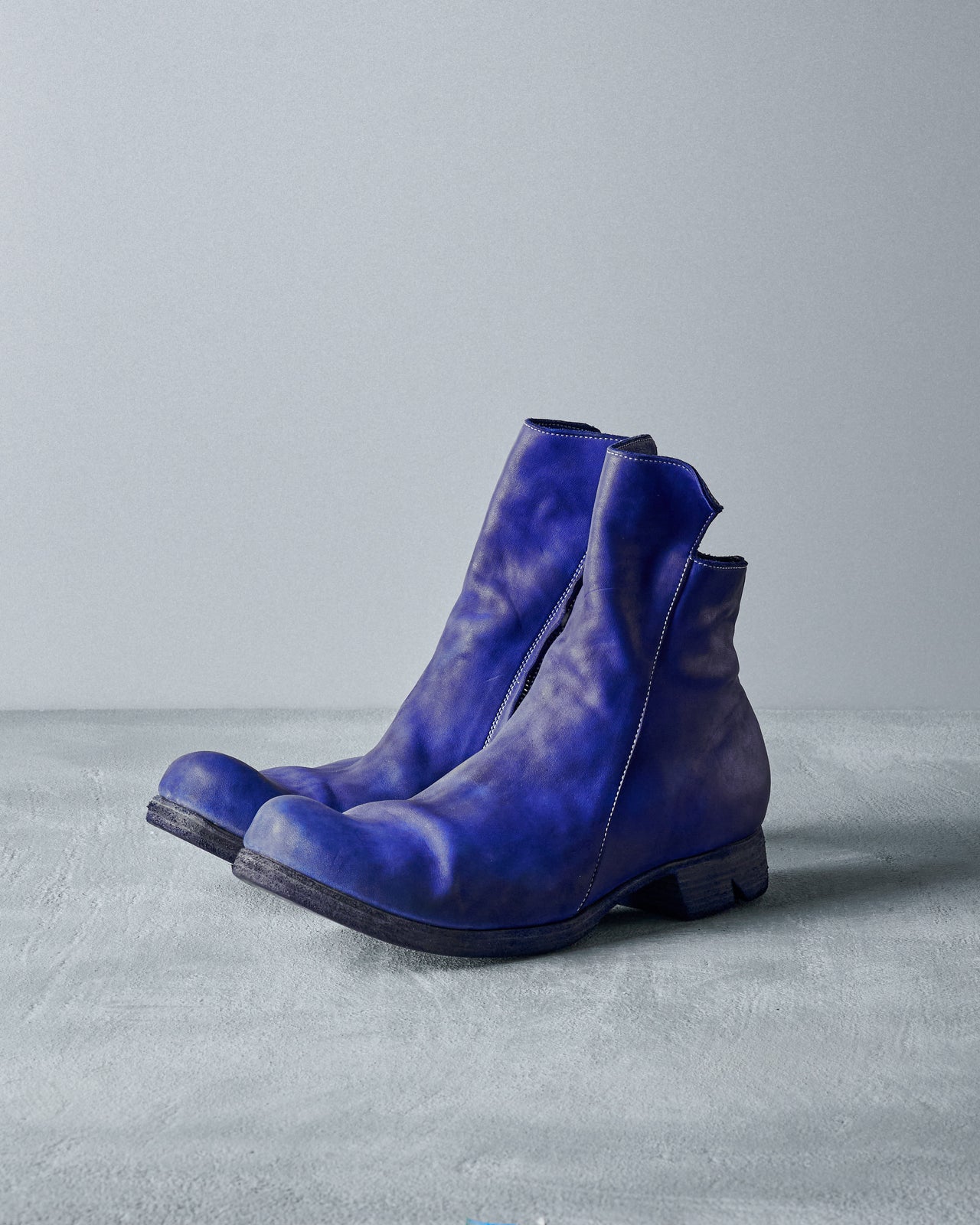 A single blue leather Boris Bidjan Saberi boot sits on a textured grey surface against a plain backdrop.