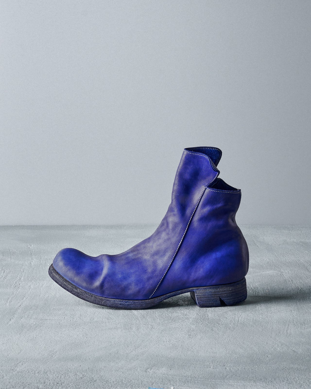 A single blue leather Boris Bidjan Saberi boot sits on a textured grey surface against a plain backdrop.