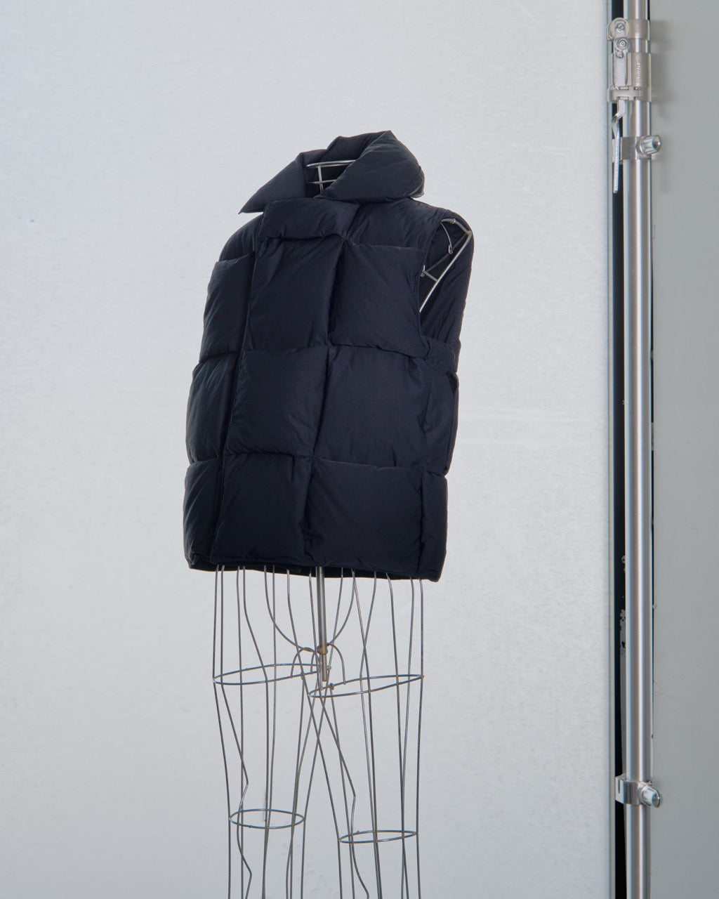 Black Bottega Veneta puffer vest on a mannequin against a light gray background