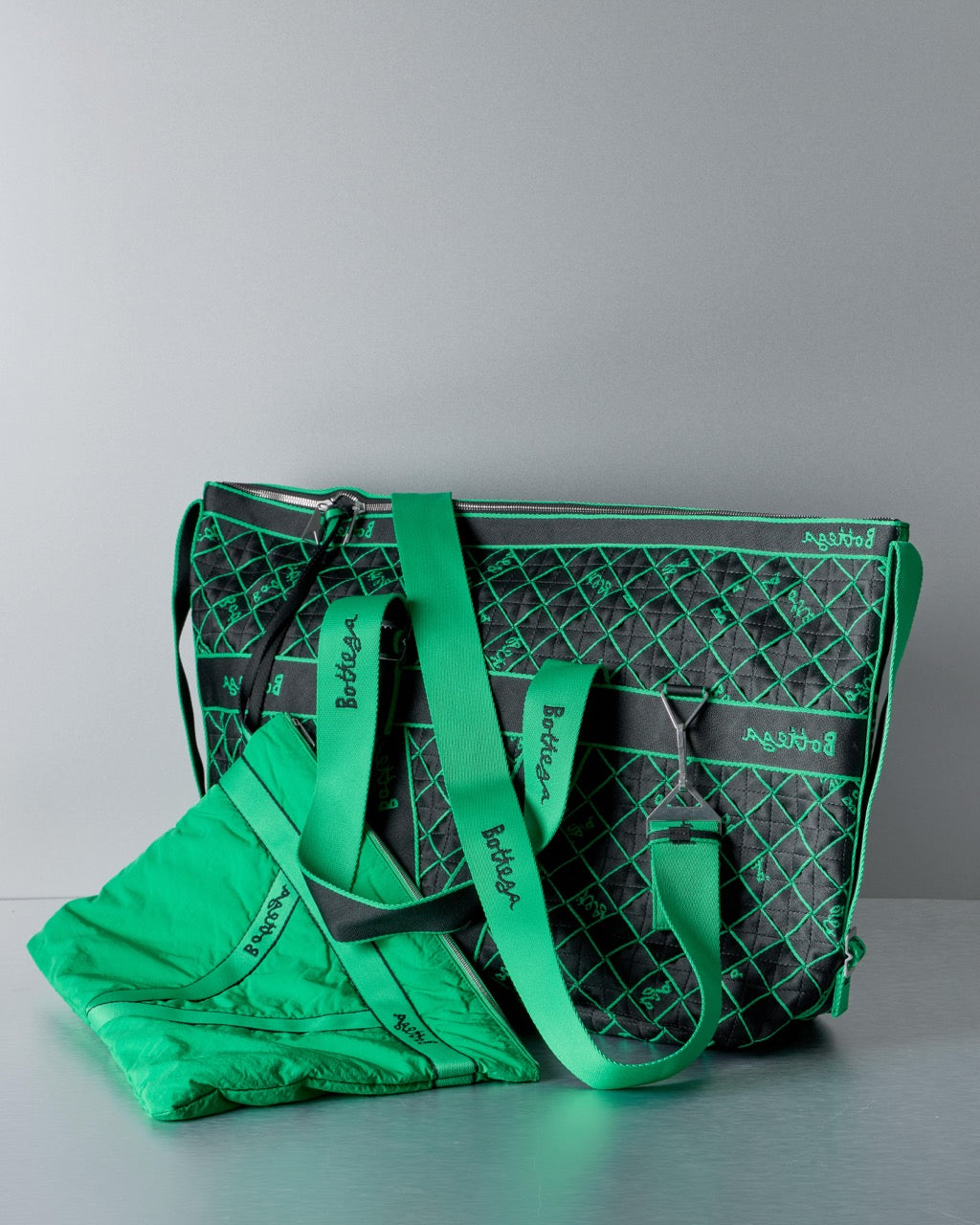 Green and black patterned Bottega Veneta tote bag on a gray background