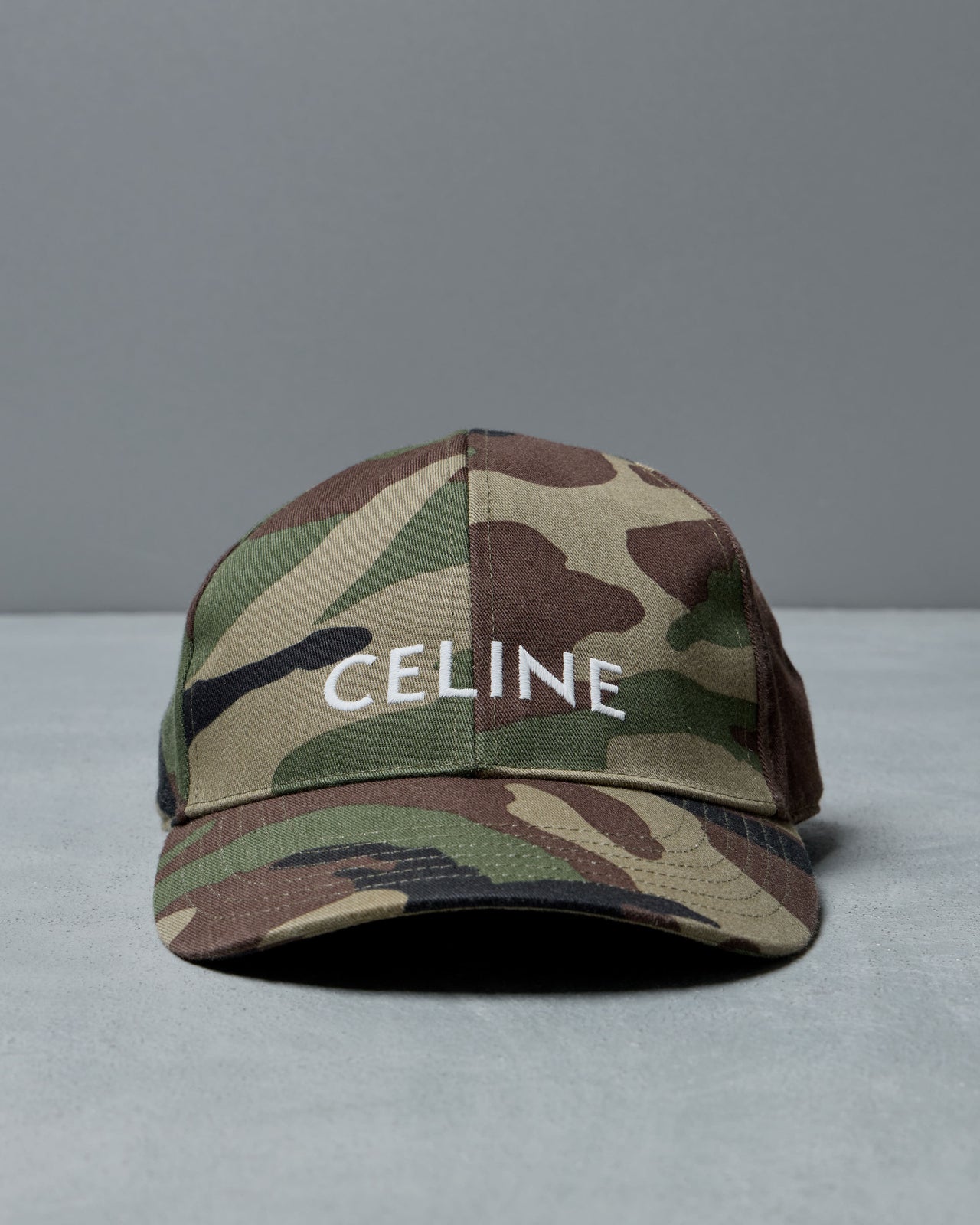 Camouflage cap with 'CELINE' branding on a gray background