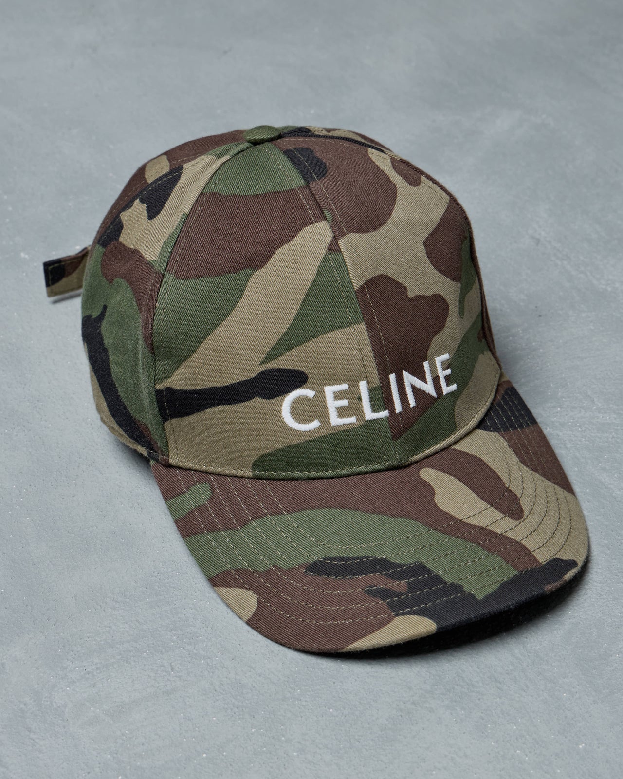 Camouflage cap with 'CELINE' branding on a gray background