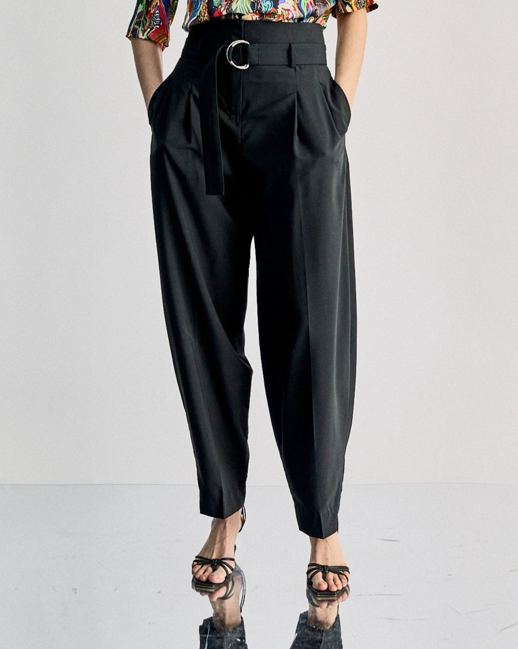 A model wearing Celine high-waist pleated trousers with a belt, featuring a black and white colour scheme.