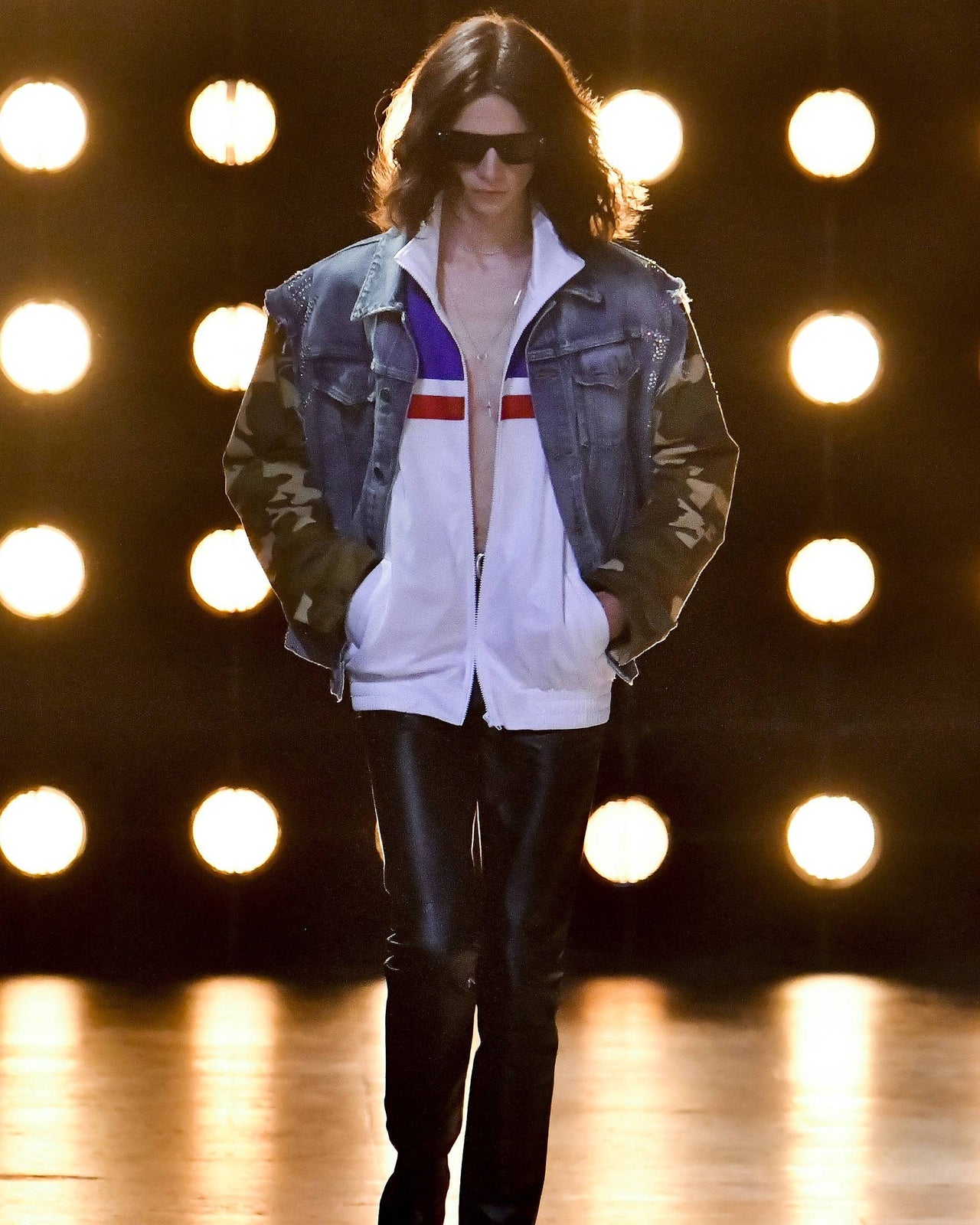 Model walking on a Celine runway with bright lights in the background