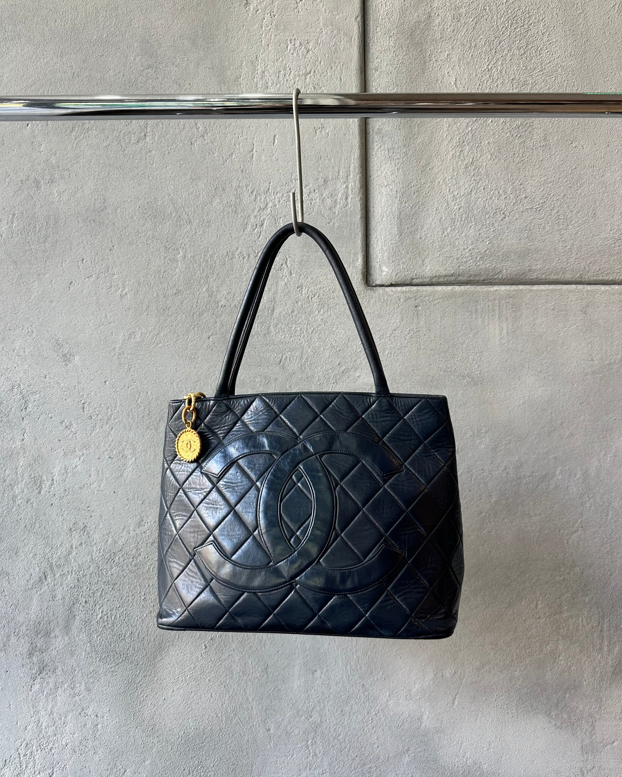 Navy quilted Chanel handbag with a gold clasp on a gray textured background