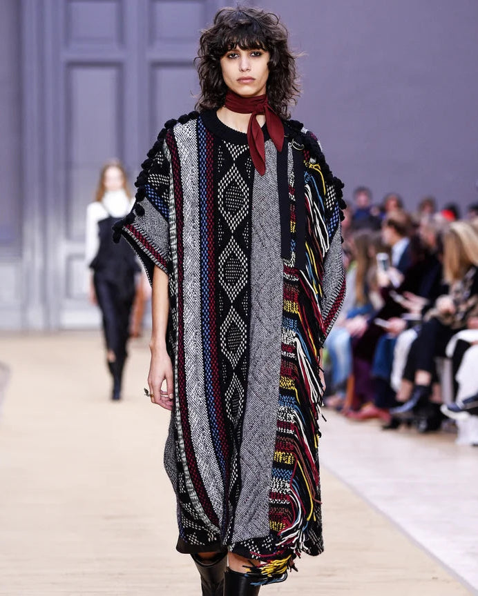 Model walking on a fashion show runway wearing a patterned Chloe poncho.