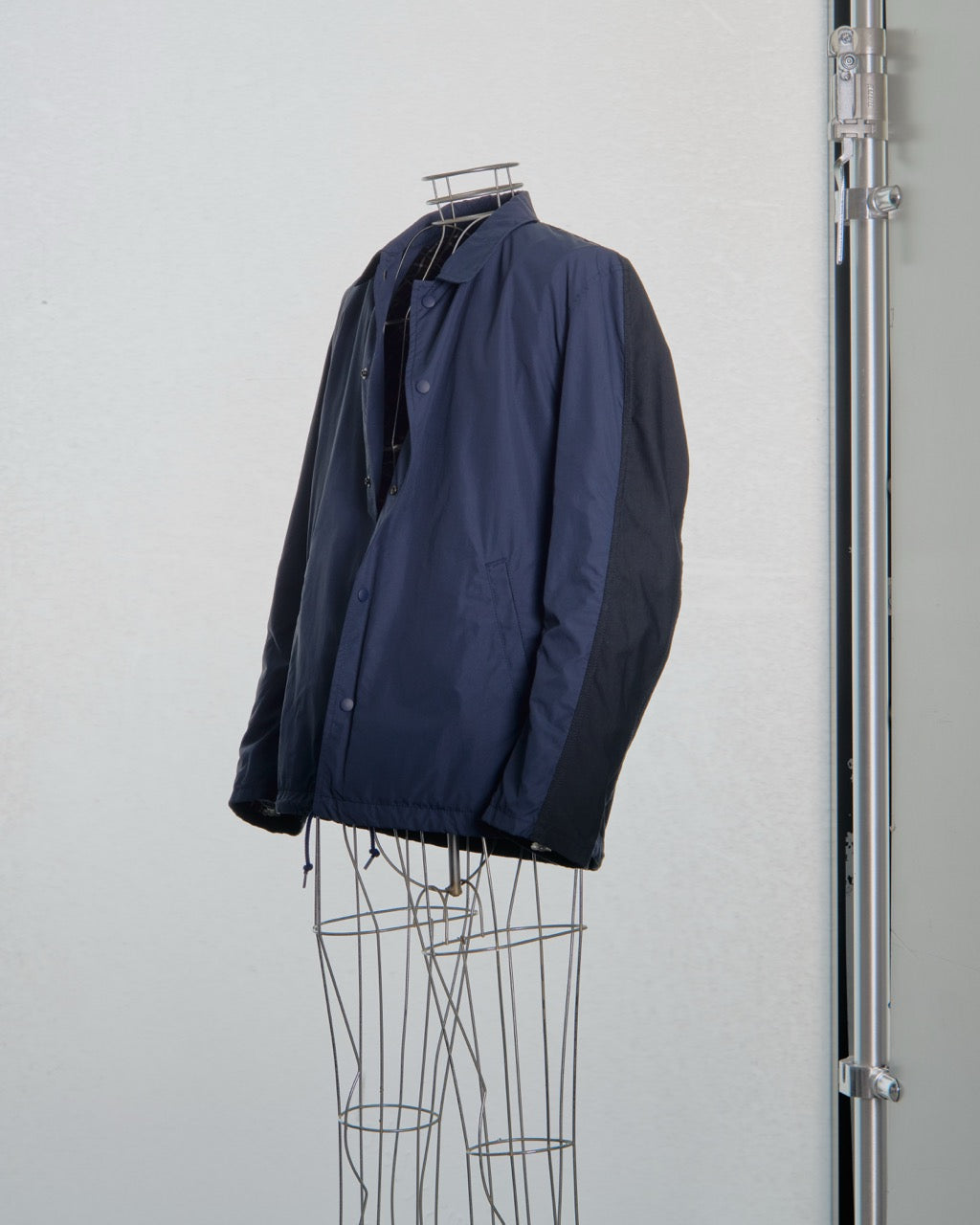 Navy blue Comme des Garcons jacket on a wire rack against a white background