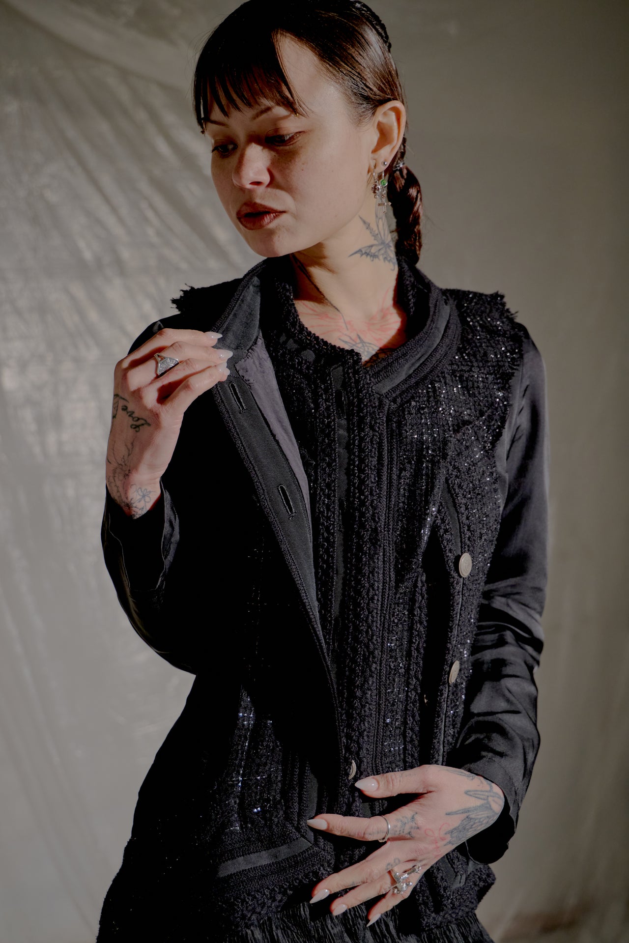 Person wearing a black Comme des Garçons Junya Watanabe jacket with intricate details against a neutral background.