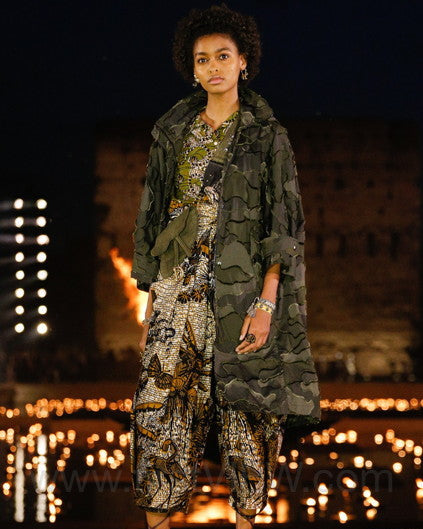 Model on a Dior runway wearing a patterned outfit with a dark background