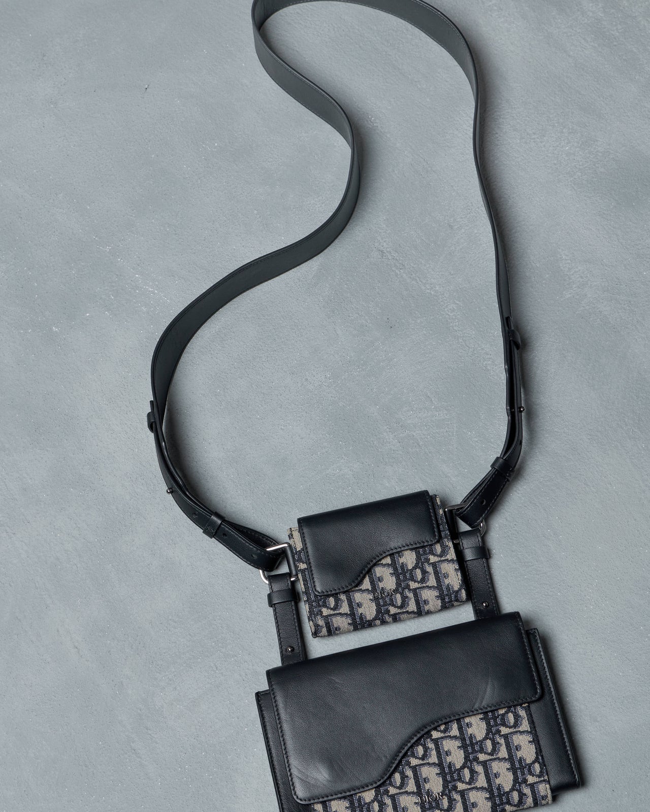 Black Dior handbag with patterned design on a gray background