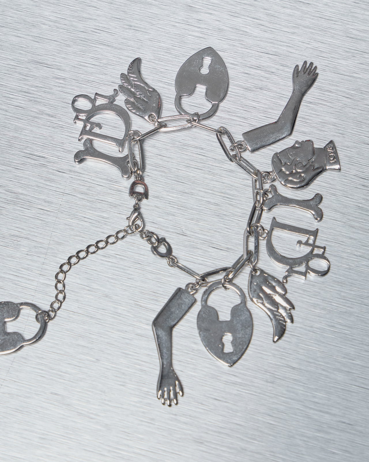 Silver Dior charm bracelet on a metallic surface