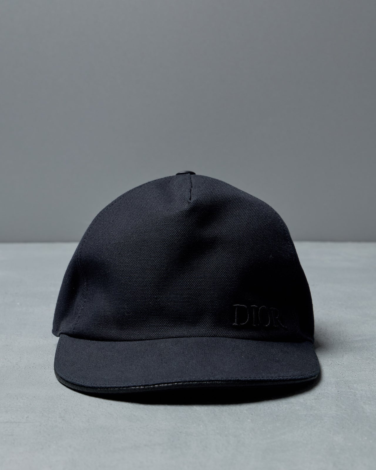 Black Dior cap with a brand logo on a gray background