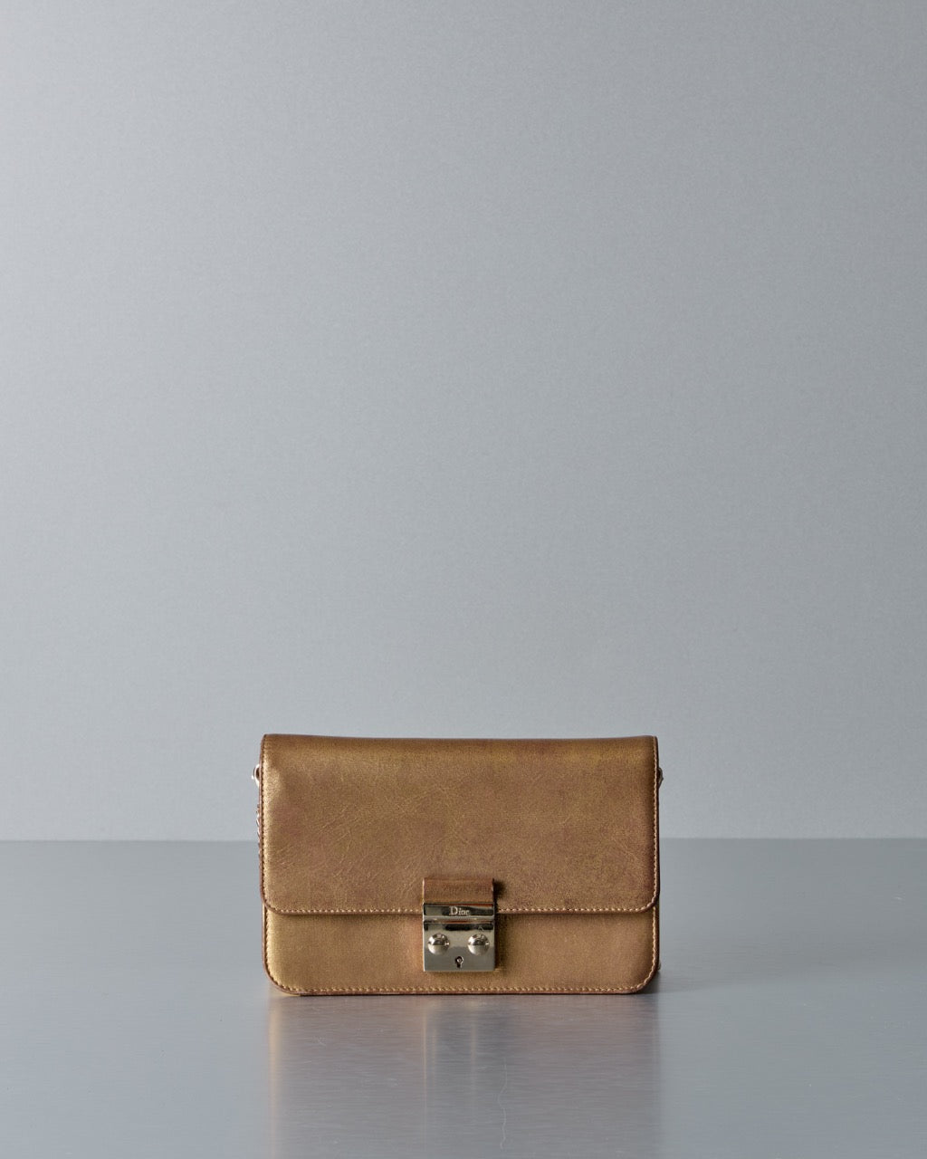 Gold Dior handbag with a chain detail on a gray background