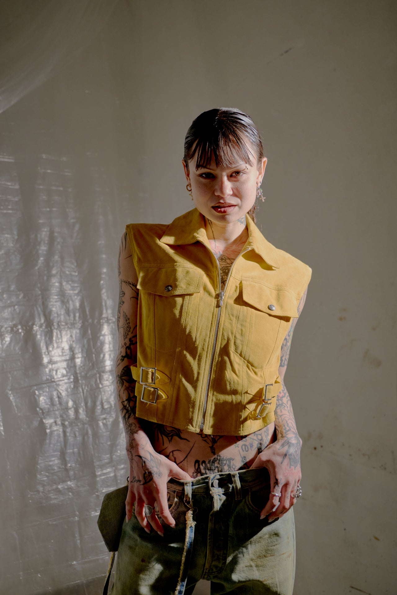 Young person in a yellow Dior jacket and jeans. The backdrop features translucent drapery.