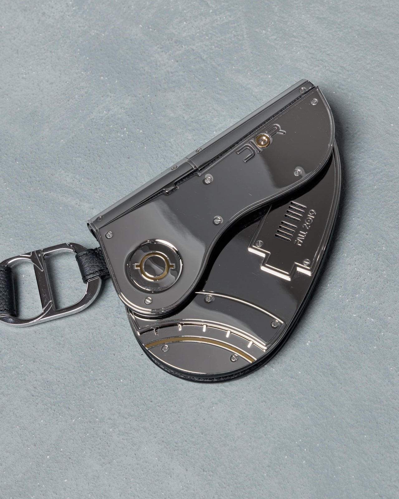 Dior x Sorayama clutch bag with keychain attachment on a gray background