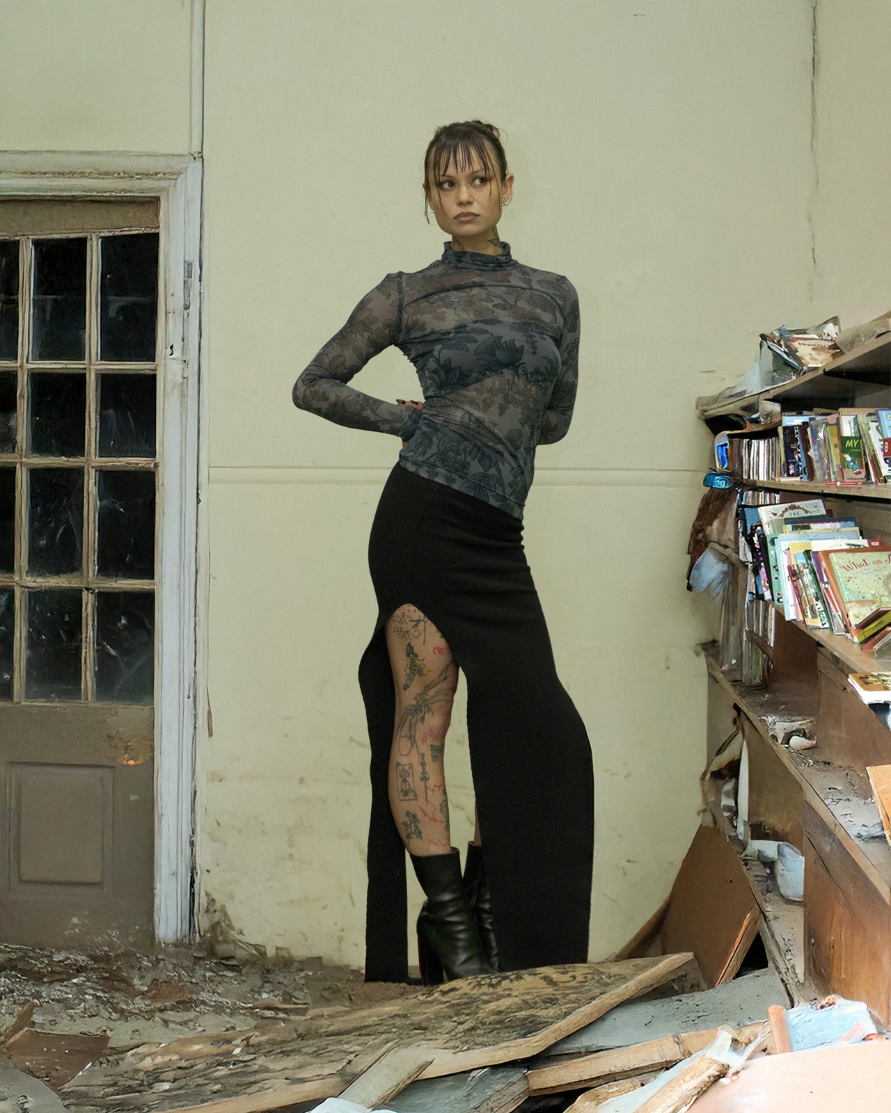 A person wearing a floral Dries Van Noten turtleneck long-sleeve top in a dilapidated room with books and debris around.