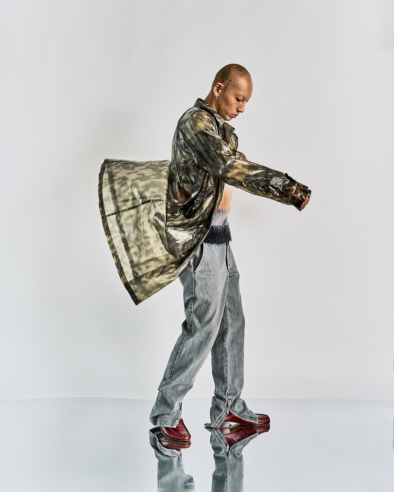 A person modeling a Dries Van Noten SS 2013 Silk camouflage coat with button-up details and raglan shoulders, featuring hip pockets and wood grain buttons.