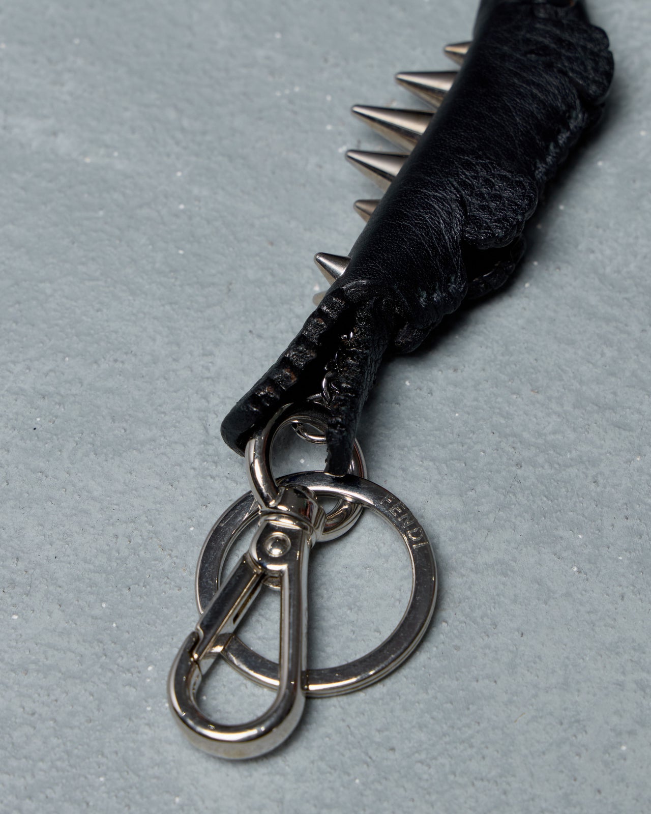 Black Fendi spiked keychain on a gray background