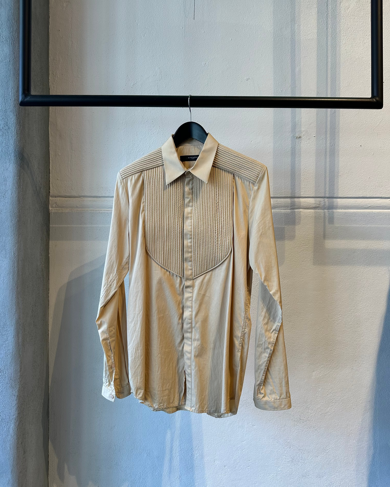 Beige Givenchy shirt on a hanger against a neutral background