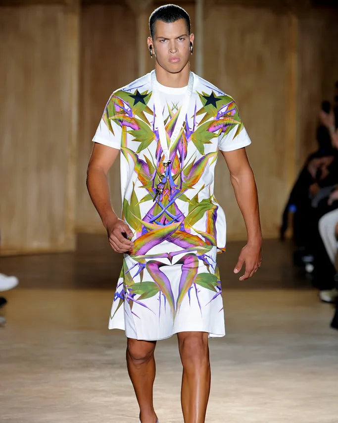 Model walking on a Givenchy runway wearing a colorful tropical-themed outfit.