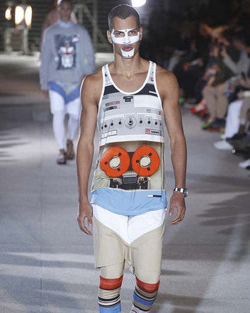 Model walking on a Givenchy runway wearing a unique tank top and colorful socks.