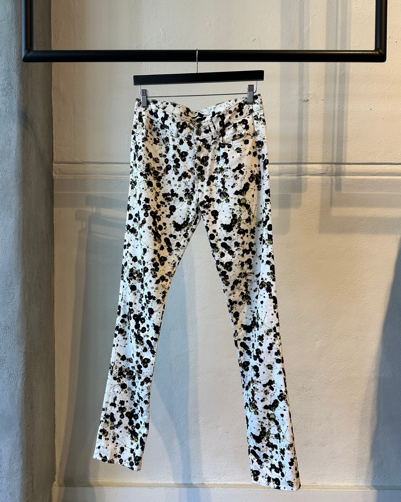 Model wearing a black and white patterned floral Givenchy outfit on a runway with an audience.