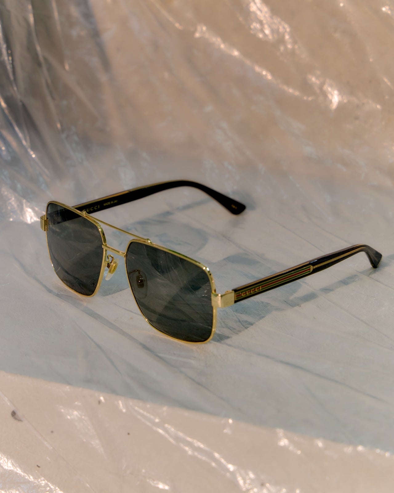 Gold-framed Gucci sunglasses on a reflective surface