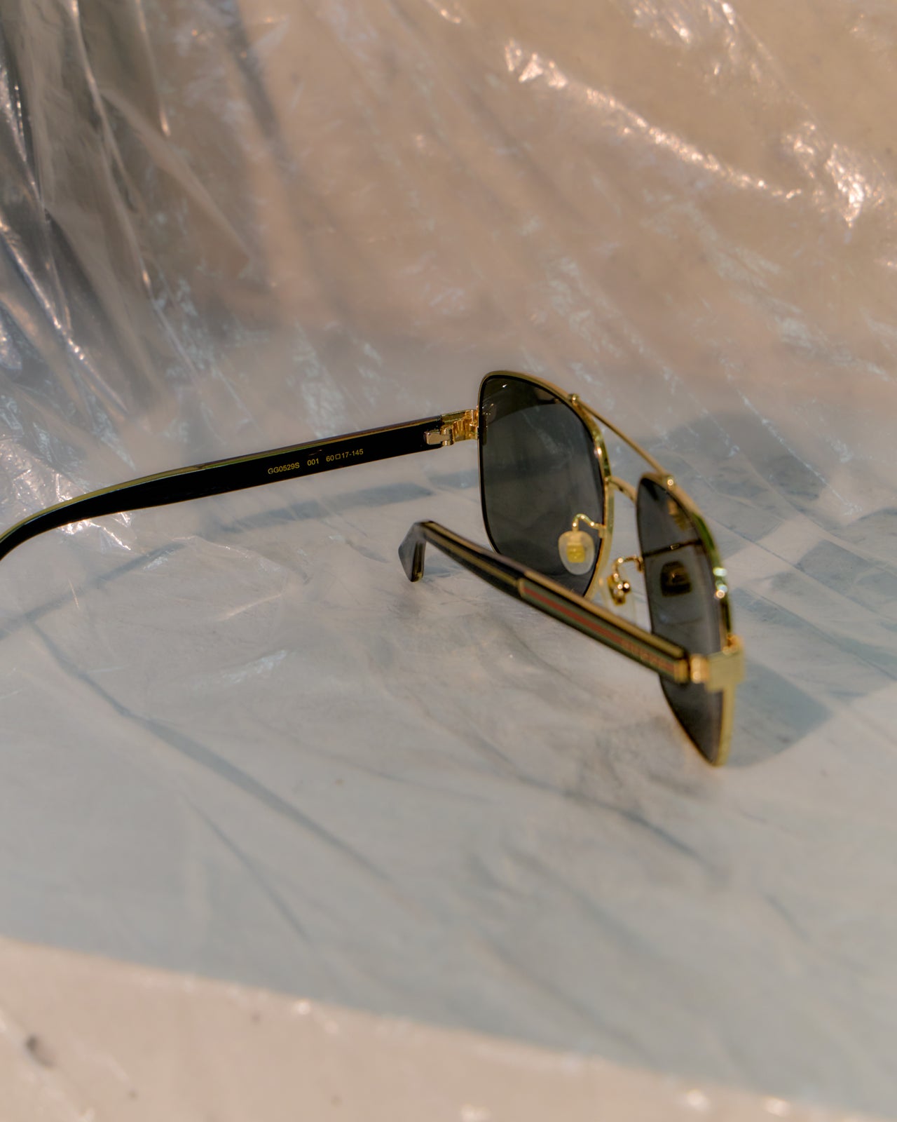 Gold-framed Gucci sunglasses on a reflective surface