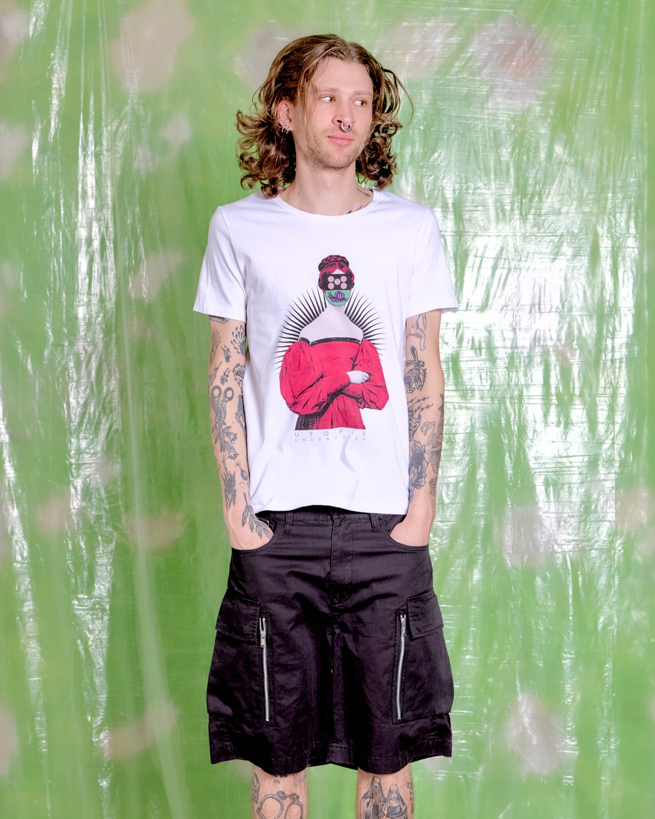 Person wearing a white t-shirt with a graphic design against a green textured background