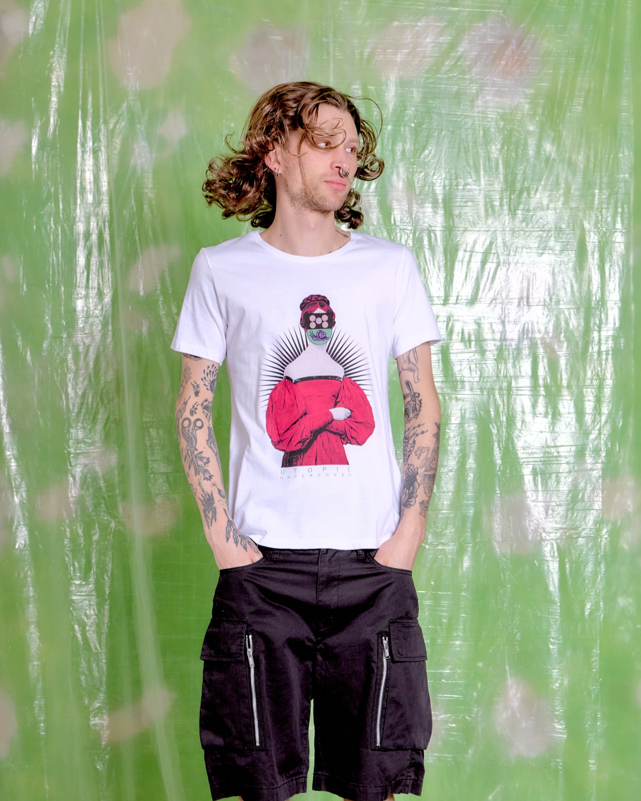 Person wearing a white t-shirt with a graphic design against a green textured background