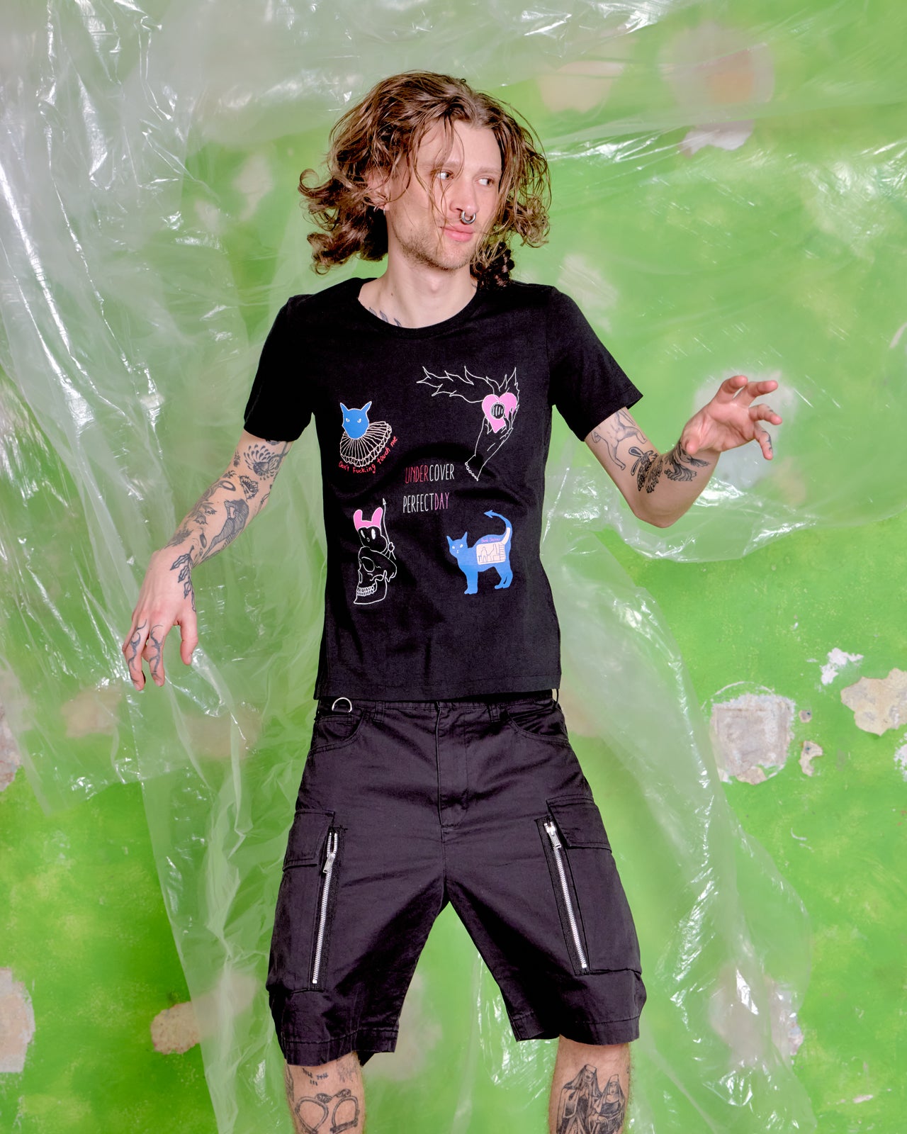 Person wearing a black t-shirt with graphic designs against a green background