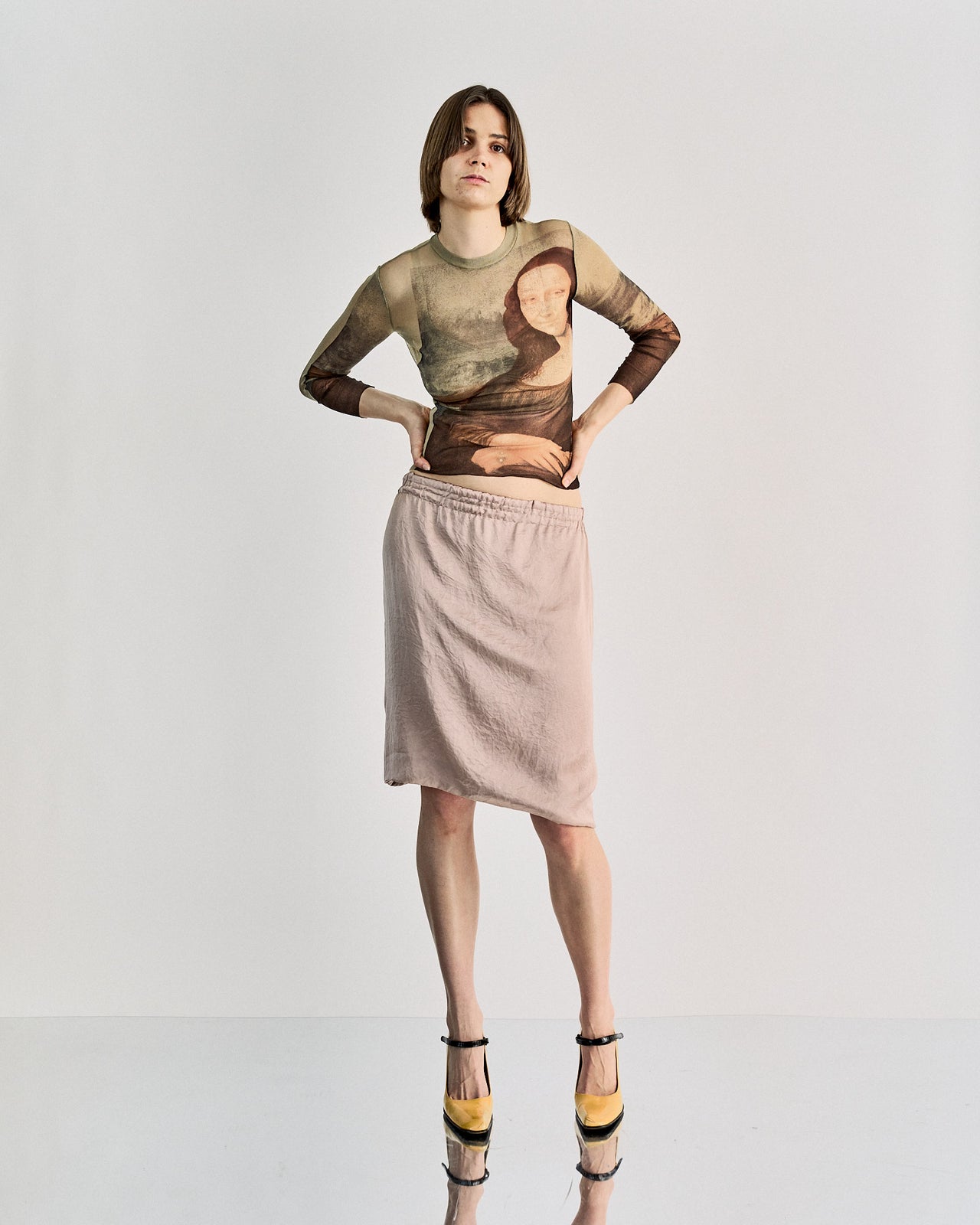 A woman standing wearing a Lanvin silk skirt with a ruched elastic waistband, in a beige color, with a visible brand mark on the skirt.