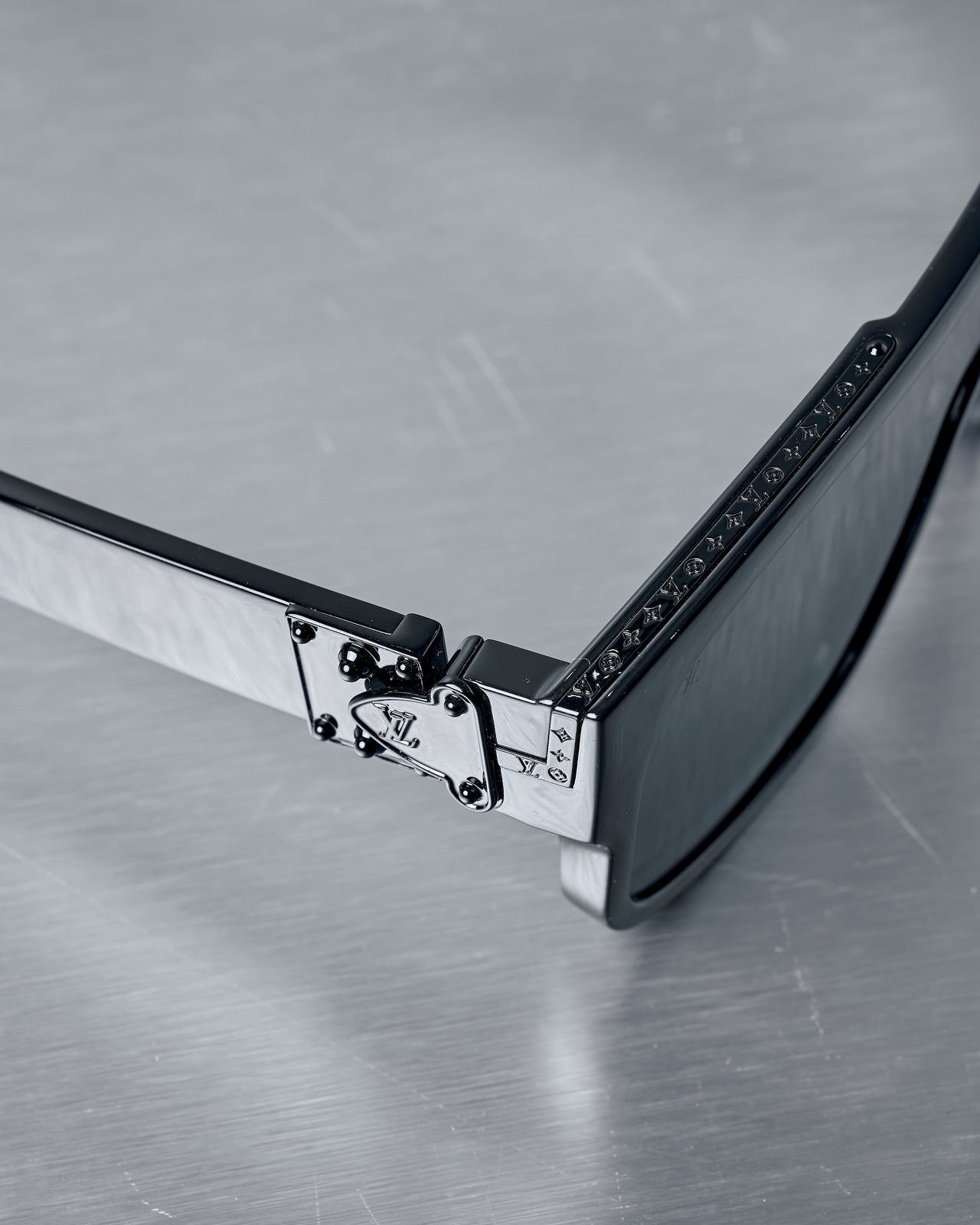Black Louis Vuitton sunglasses with a reflective surface on a grey background